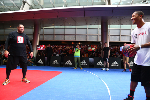 Derrick Rose of the Chicago Bulls faces off against a sumo wrestler at the 1 on 100 event.